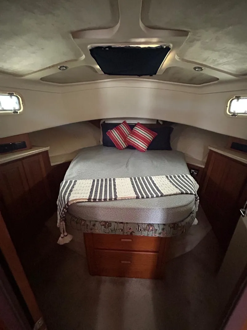 Slide: The Image of 1999 Mainship 350 Trawler cabin with cozy bed, striped blanket, and decorative pillows. - 6