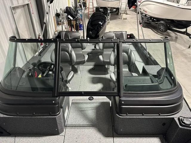 Slide: The Image of 2025 Lund 1775 Impact XS Sport boat interior with seating and windshield in a showroom. - 24