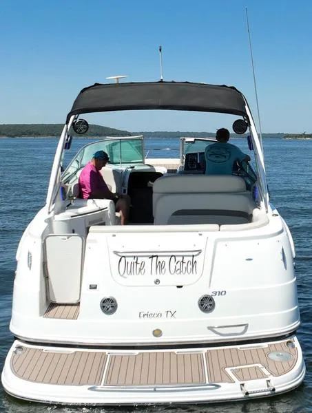 Slide: The Image of 2009 Chaparral 310 Signature boat on water, rear view, with two people onboard. - 20