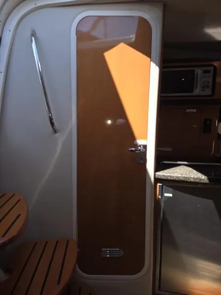 Slide: The Image of 2009 Chaparral 310 Signature cabin interior with wooden door and kitchenette. - 29