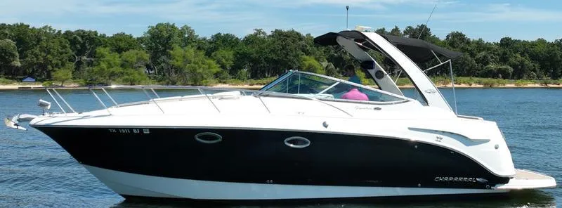 Slide: The Image of 2009 Chaparral 310 Signature boat cruising on a lake with lush green shoreline. - 3