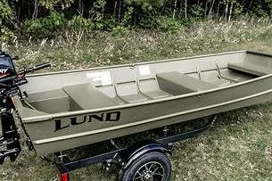 Slide: The Image of 2024 Lund 1448 Jon Tiller boat on trailer, parked on grassy area near trees. - 4