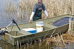 Slide: The Image of 2024 Lund 1448 Jon Tiller boat in marsh, with man and fishing gear. - 6