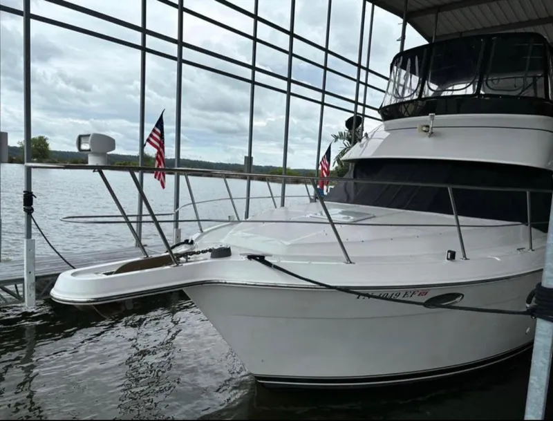 Slide: The Image of 2001 Carver 356 Motor Yacht docked with American flags, under a covered marina. - 3