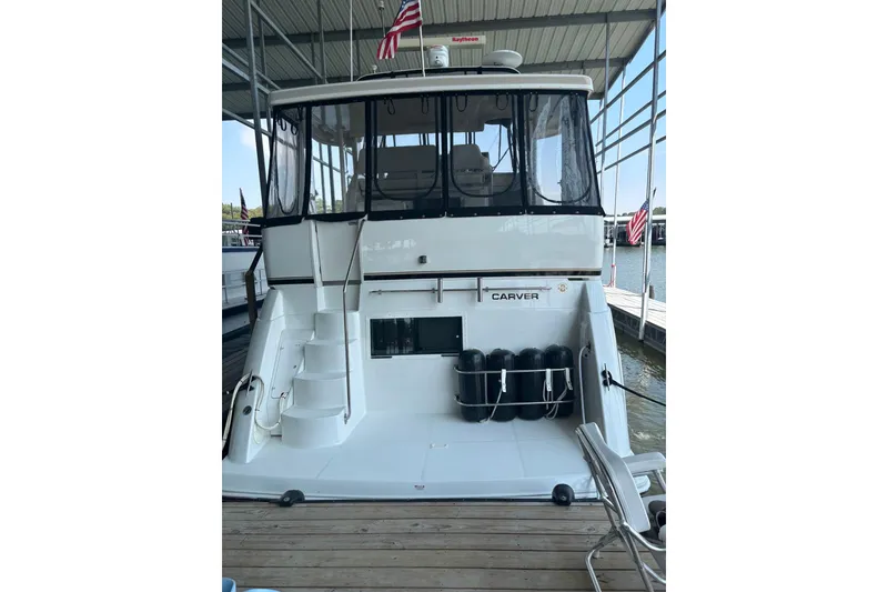 Slide: The Image of 2001 Carver 356 Motor Yacht docked, rear view with American flags and covered seating area. - 45