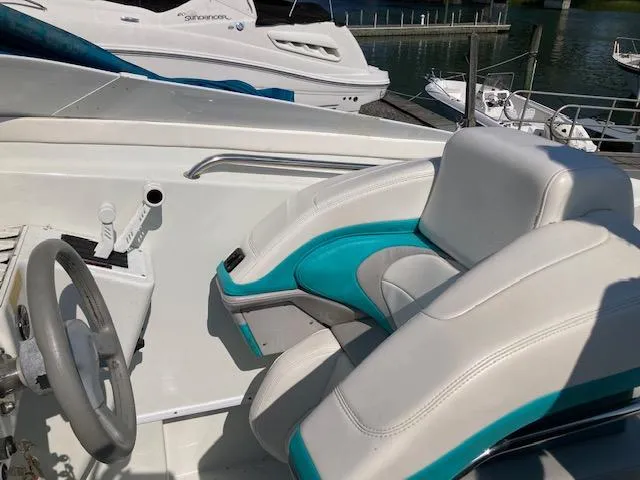 Slide: The Image of 1996 Baja 320 boat interior with white and teal seating at a marina. - 2