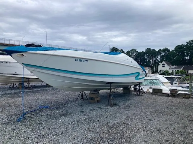 The Image of 1996 Baja 320 boat on stands in a marina, overcast sky. - 0