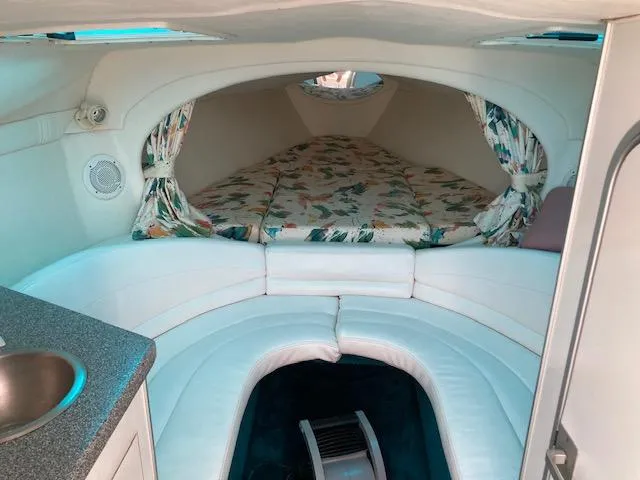 Slide: The Image of Interior of a 1996 Baja 320 boat with white seating and floral-patterned bedding. - 10