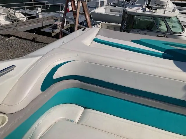 Slide: The Image of 1996 Baja 320 boat with teal and white seating at a marina. - 4