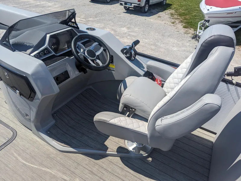 Slide: The Image of Captain's seat and helm of 2022 Manitou Encore 25 RF pontoon boat, featuring modern controls. - 17