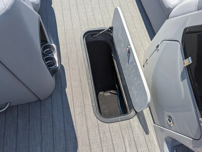 Slide: The Image of Open storage compartment on 2022 Manitou Encore 25 RF boat with gray flooring. - 23