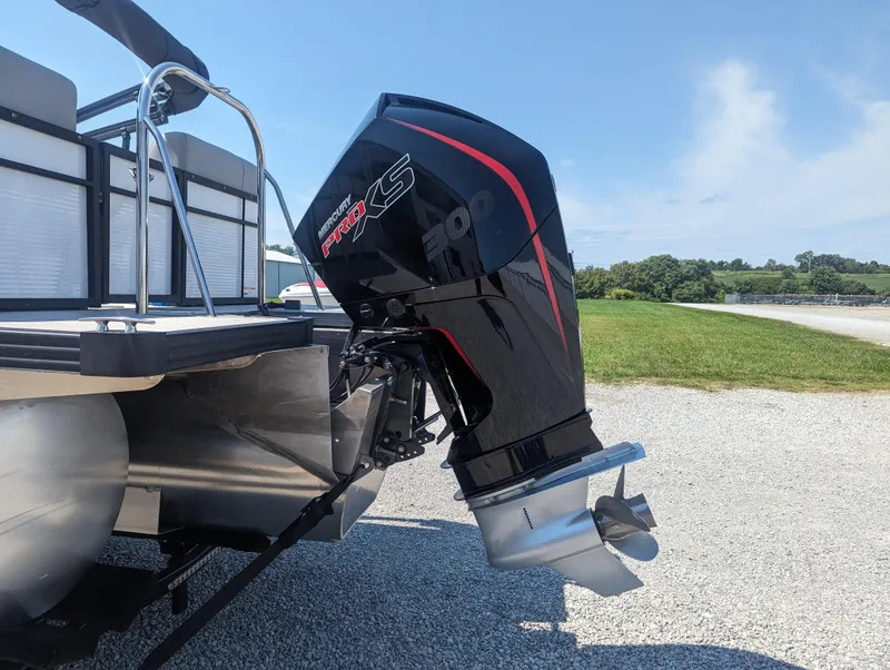 Slide: The Image of 2022 Manitou Encore 25 RF boat with powerful outboard motor on gravel surface. - 9
