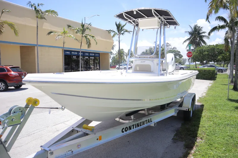 Slide: The Image of 2025 Bulls Bay 2200 boat on trailer, parked near palm trees and building. - 1