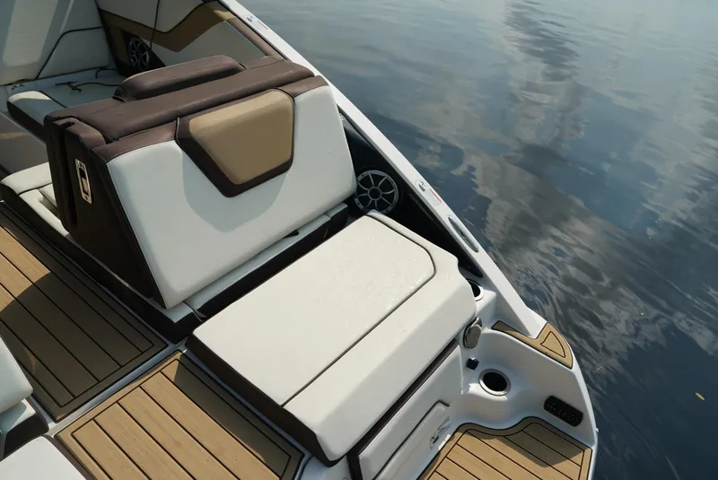 Slide: The Image of 2021 Yamaha Boats 252SE interior with luxurious seating and wood accents on calm water. - 20