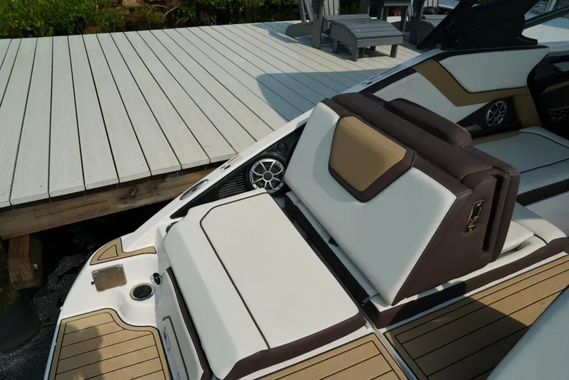 Slide: The Image of 2021 Yamaha Boats 252SE interior with white and tan seating near a dock. - 21
