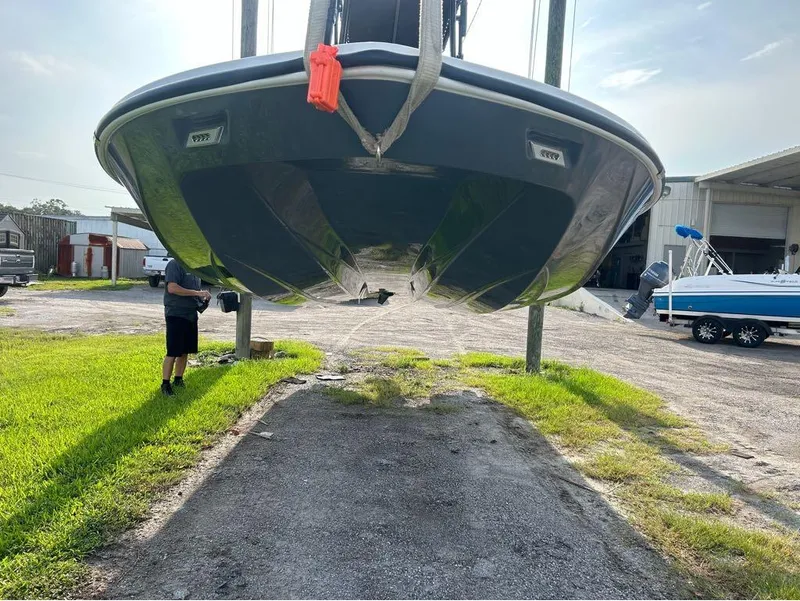 Slide: The Image of 2025 Tidewater 25 TPC Raptor boat suspended, outdoor setting, person inspecting. - 3