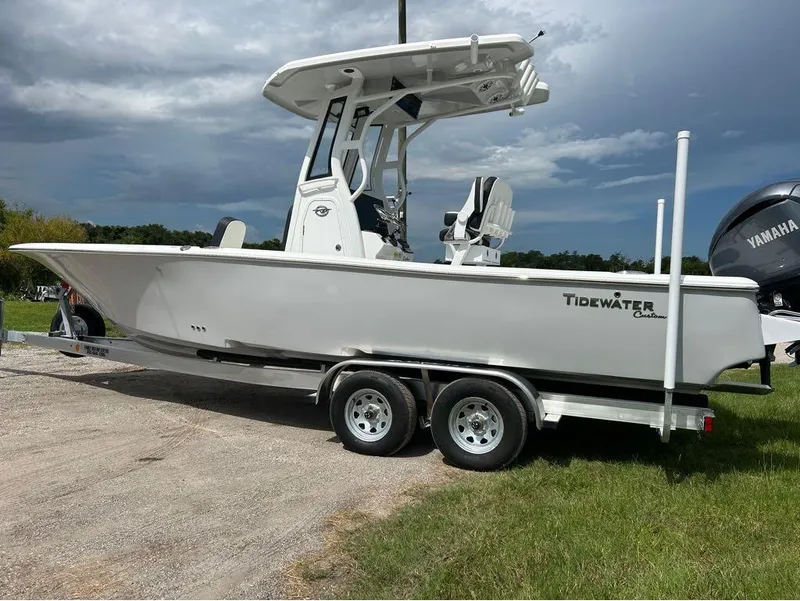 Slide: The Image of 2025 Tidewater 2500 Carolina Bay boat on trailer, parked on grass under cloudy sky. - 12