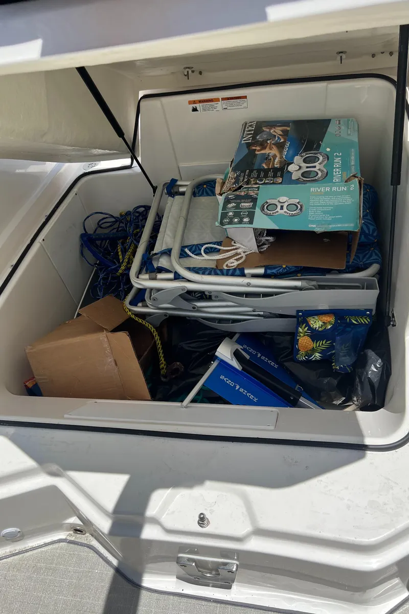 Slide: The Image of Open storage compartment on 2021 Regal 21 OBX boat filled with various items. - 15