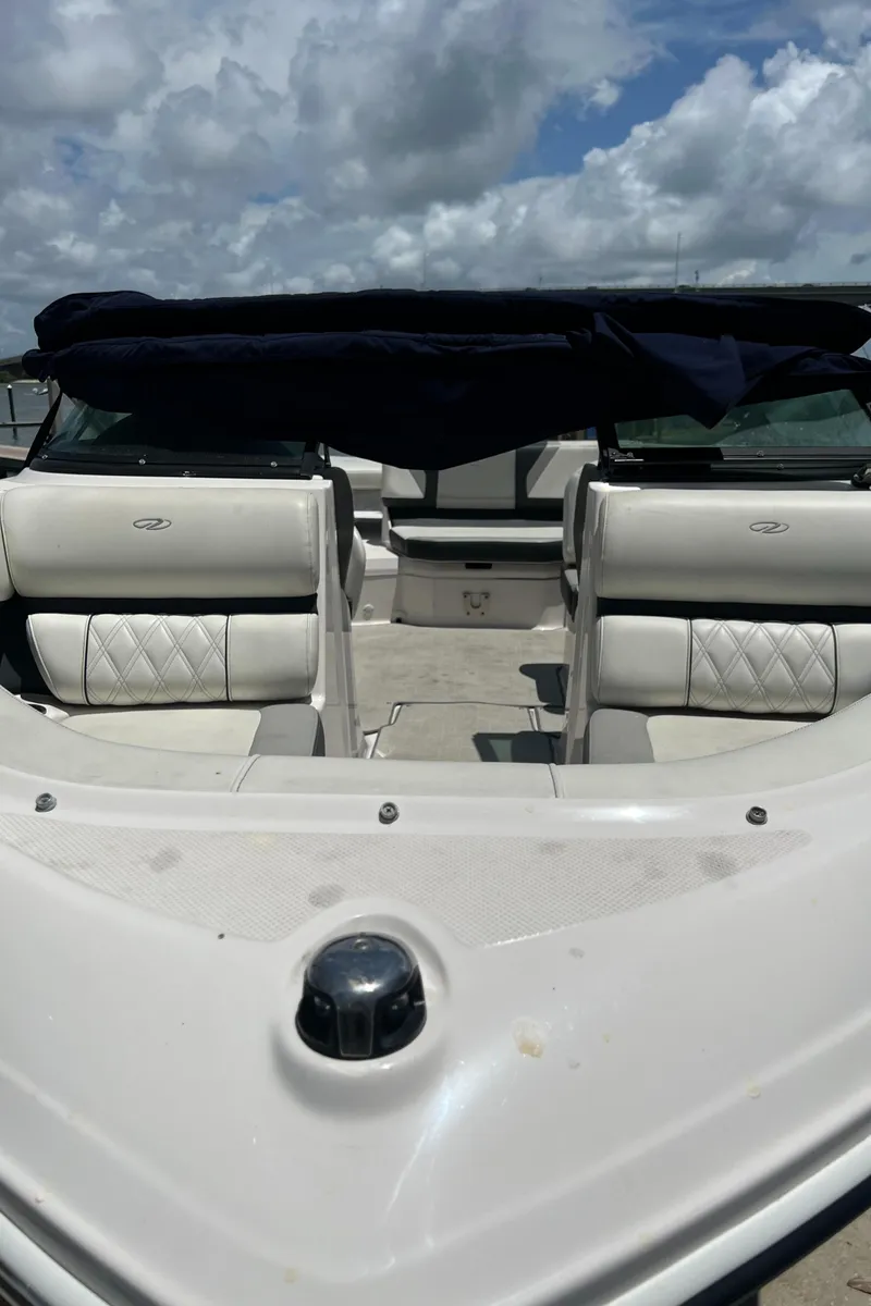 Slide: The Image of 2021 Regal 21 OBX boat with white seating and blue canopy under cloudy sky. - 16