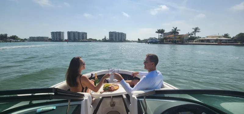 Slide: The Image of Couple enjoying a meal on a 2021 Regal 21 OBX boat, with scenic waterfront views. - 19