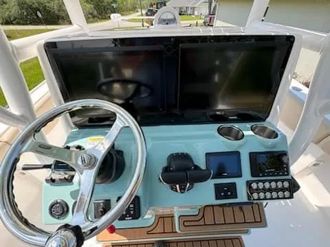 Slide: The Image of 2024 Tidewater 2700 Carolina Bay boat dashboard with dual screens and steering wheel. - 2
