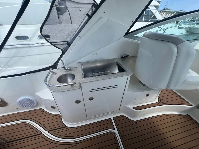 Slide: The Image of 2010 Sea Ray 350 Sundancer cockpit with sink and seating, featuring teak flooring. - 18