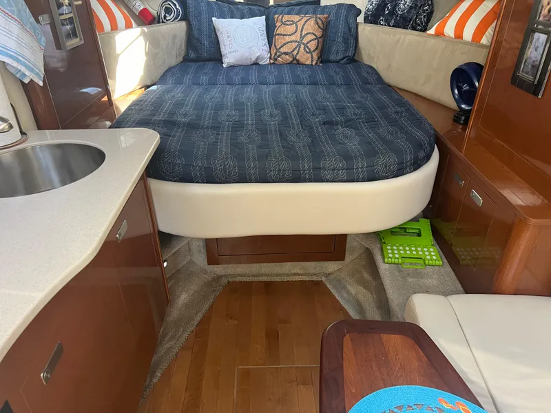 Slide: The Image of 2010 Sea Ray 350 Sundancer cabin interior with bed, pillows, and kitchenette. - 24