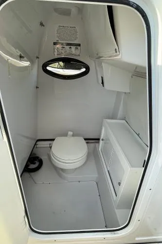 Slide: The Image of 2019 Sportsman 282 boat interior with compact marine toilet and storage cabinet. - 16