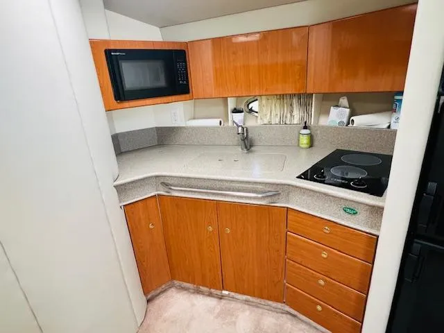 Slide: The Image of Compact kitchen in a 2000 Formula 41 PC boat with wood cabinets and modern appliances. - 10