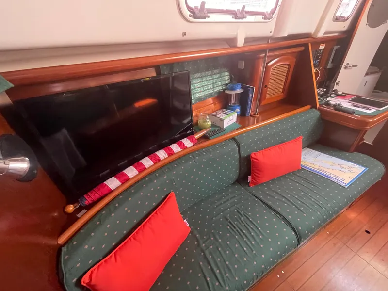 Slide: The Image of Interior of 1999 Beneteau Oceanis 36 CC yacht with green sofa, red cushions, and mounted TV. - 14