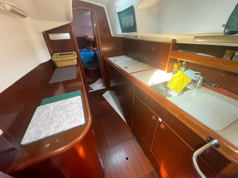 Slide: The Image of 1999 Beneteau Oceanis 36 CC yacht interior with wooden cabinetry and compact kitchen area. - 17
