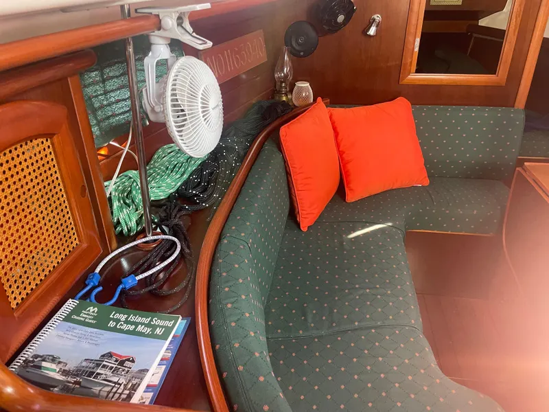 Slide: The Image of Interior of 1999 Beneteau Oceanis 36 CC with green seating, red cushions, and nautical decor. - 18