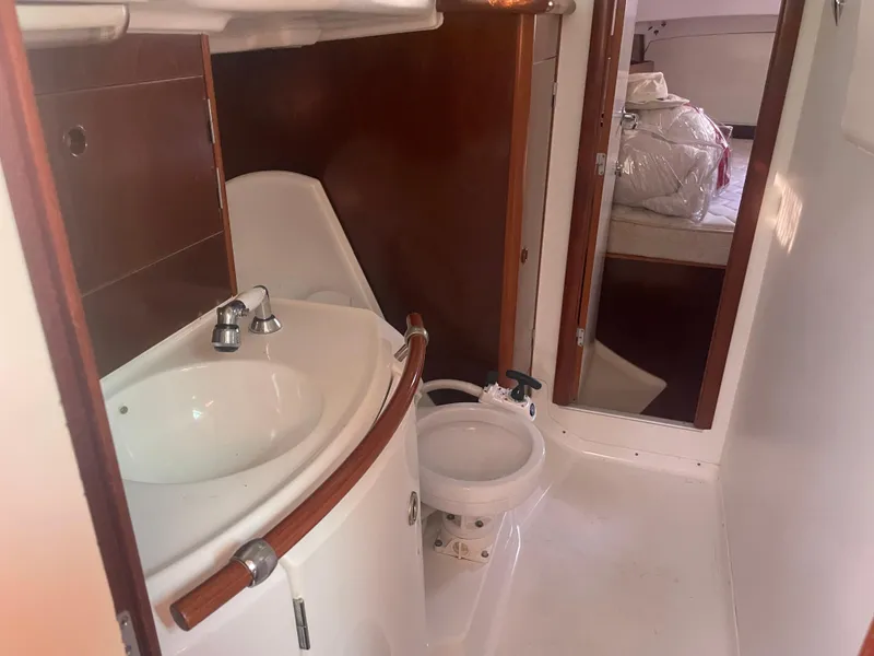 Slide: The Image of 1999 Beneteau Oceanis 36 CC bathroom with sink and toilet, featuring wooden accents. - 19