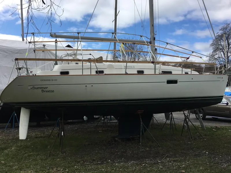 Slide: The Image of 1999 Beneteau Oceanis 36 CC sailboat on stands, named "Summer Breeze," under a partly cloudy sky. - 23