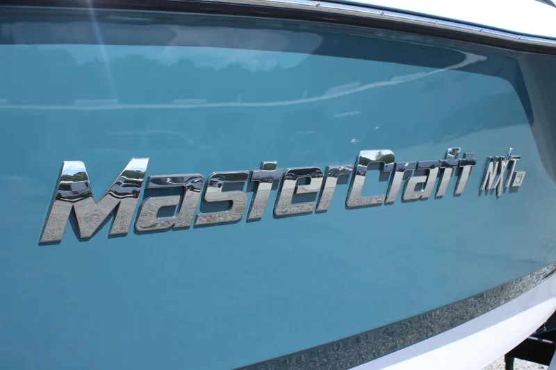 Slide: The Image of 2025 MasterCraft NXT21 boat with sleek blue exterior and chrome logo. - 12