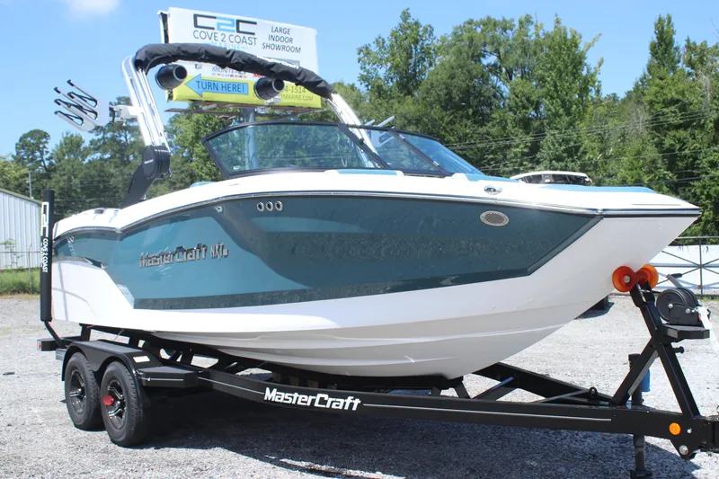 Slide: The Image of 2025 MasterCraft NXT21 boat on trailer, parked outdoors, with trees in the background. - 9