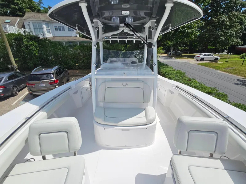 Slide: The Image of 2025 Southport 30 FE boat with white seating and console, parked near greenery and cars. - 23