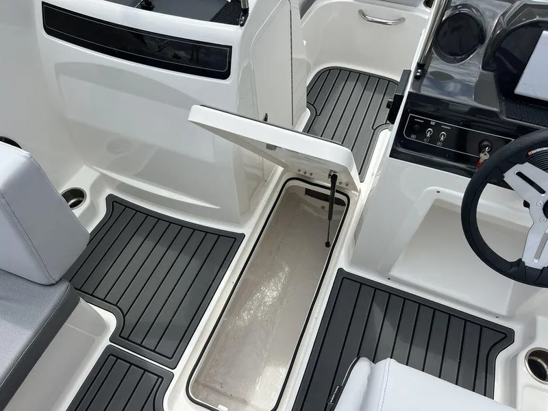 Slide: The Image of 2025 Bayliner VR4 Bowrider interior with open storage compartment and sleek black flooring. - 11
