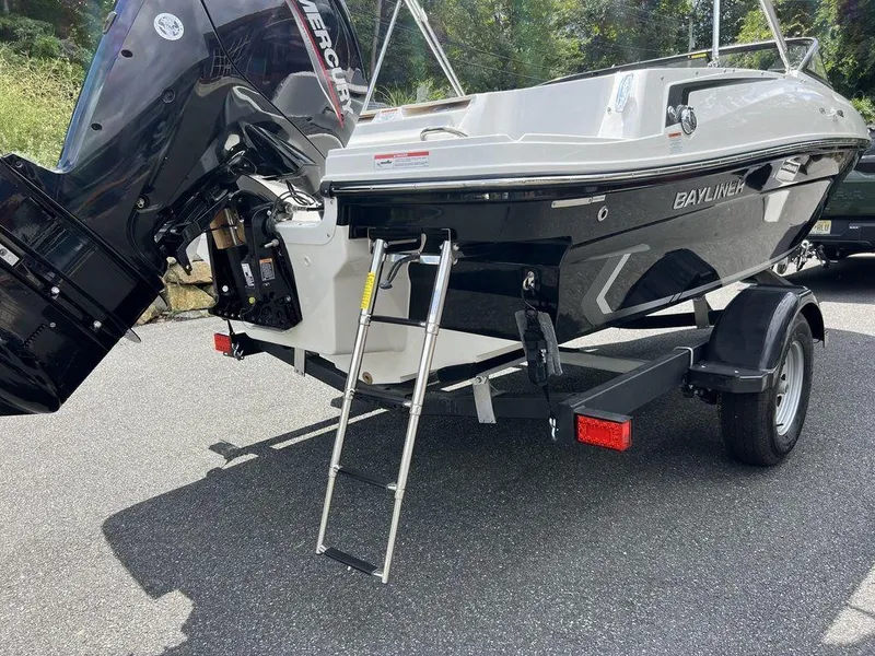 Slide: The Image of 2025 Bayliner VR4 Bowrider Outboard with ladder and trailer, parked outdoors. - 4