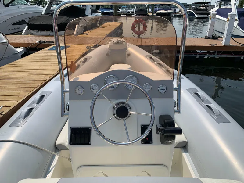 Slide: The Image of 2019 Inmar 635 boat dashboard with steering wheel, docked at marina. - 11