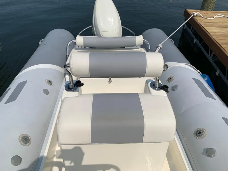 Slide: The Image of 2019 Inmar 635 inflatable boat with gray and white seating, docked by the water. - 13