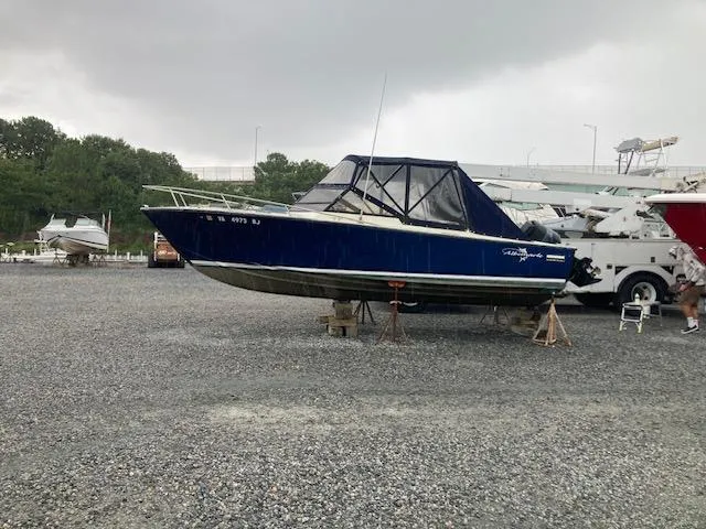The Image of 1982 Albemarle 24 boat on gravel lot under cloudy sky. - 0