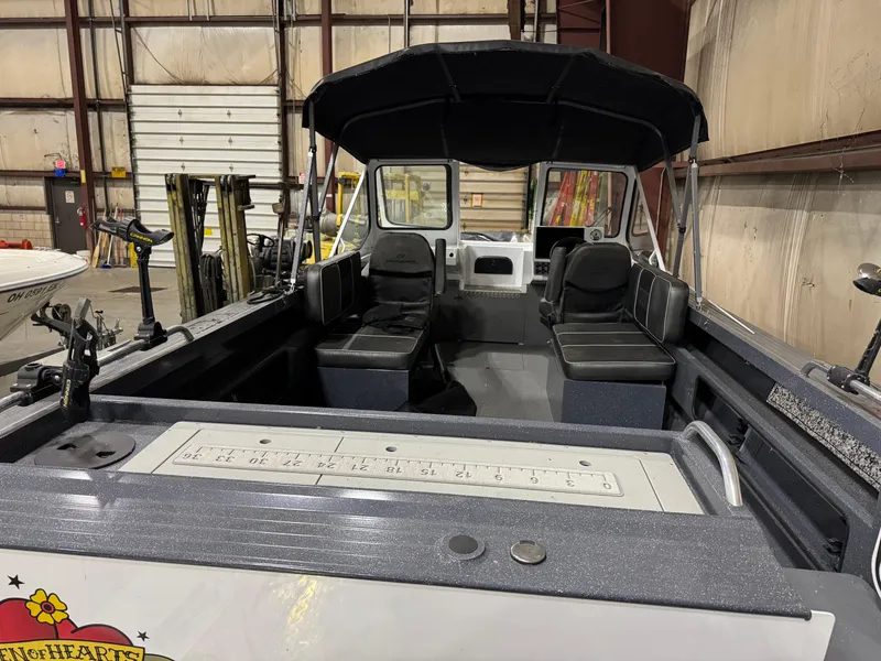 Slide: The Image of 2022 Duckworth 21 Discovery boat interior with seating, under a canopy, in a warehouse setting. - 5