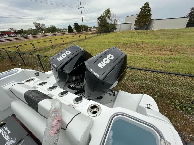 Slide: The Image of 2023 Wellcraft 262 Fisherman boat with dual Mercury 200 engines, parked near a grassy field. - 10