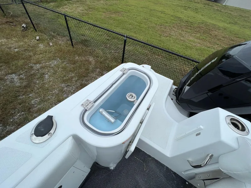 Slide: The Image of 2023 Wellcraft 262 Fisherman boat with livewell and outboard motor, parked near a fence. - 12