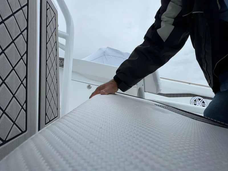 Slide: The Image of 2023 Wellcraft 262 Fisherman boat interior with textured seating and hand detail. - 27