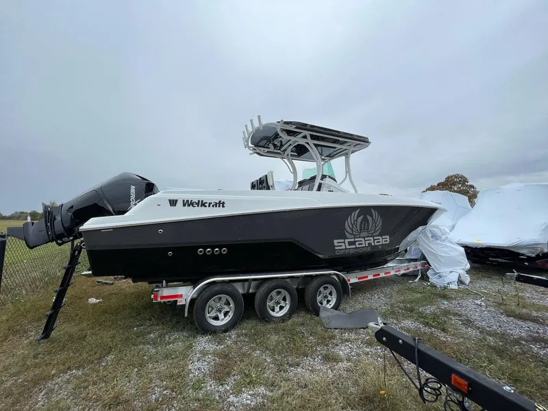 Slide: The Image of 2023 Wellcraft 262 Fisherman boat on trailer, black hull, Scarab Offshore branding. - 4