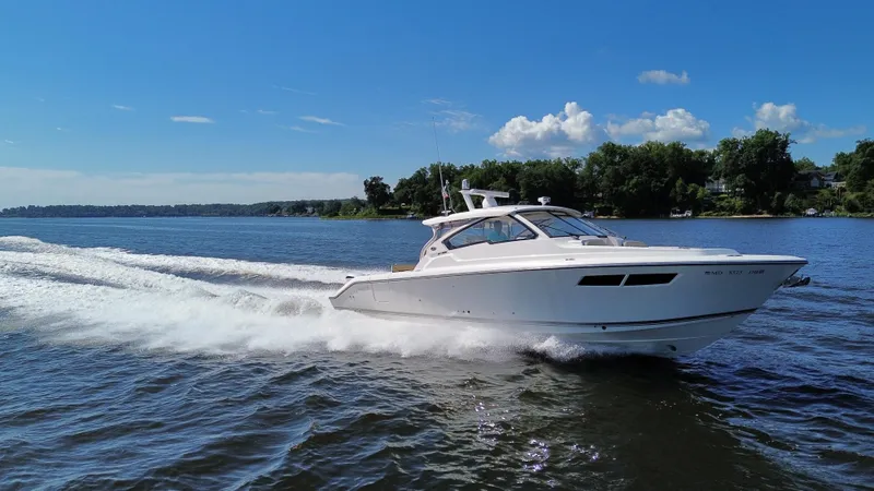 The Image of 2018 Pursuit DC 365 Dual Console boat cruising on a sunny lake. - 0
