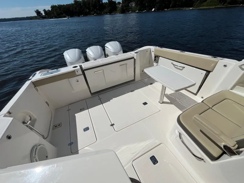 Slide: The Image of 2018 Pursuit DC 365 Dual Console boat interior with seating and table on a sunny day. - 13