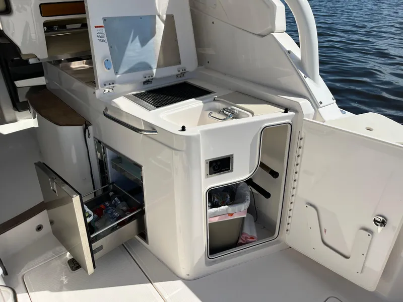 Slide: The Image of 2018 Pursuit DC 365 Dual Console boat interior with kitchenette and storage. - 17